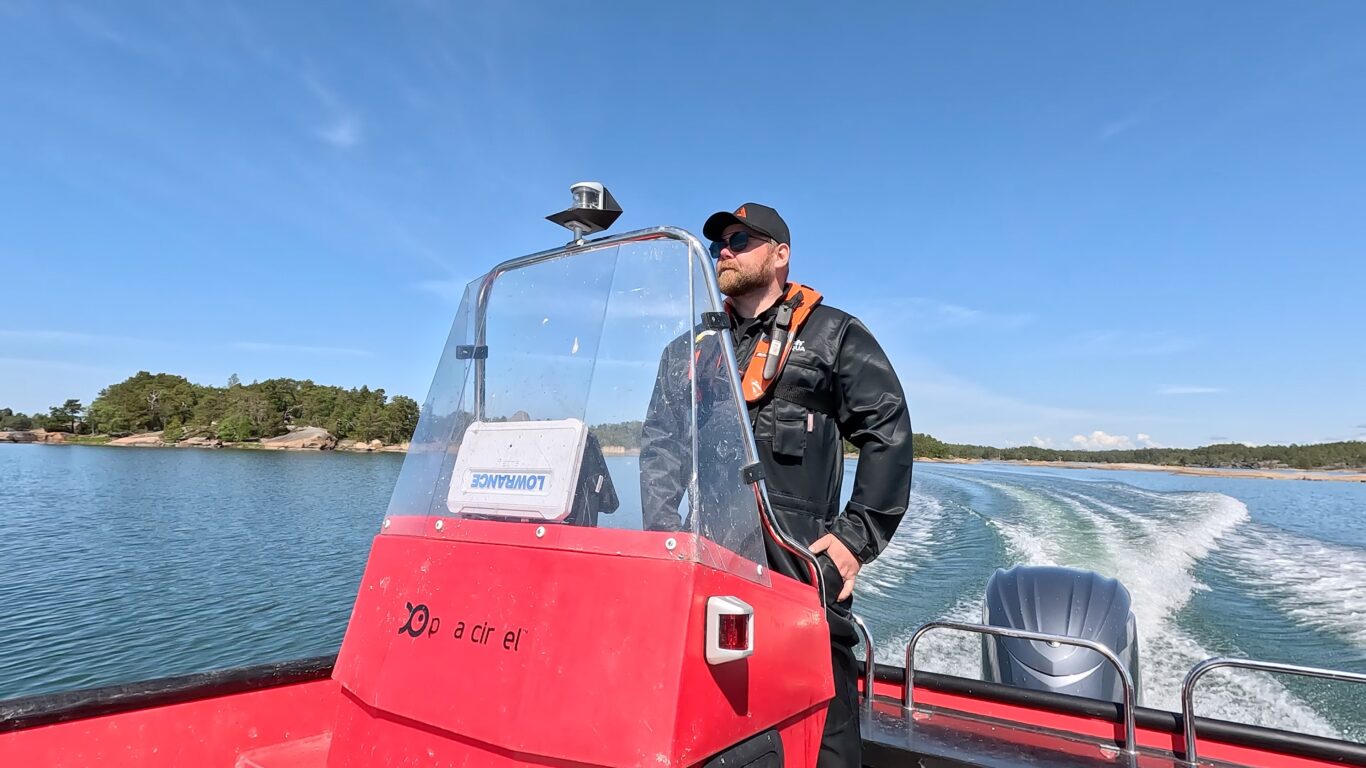 Parrakas mies ajaa moottoriveneellä kesäisessä saaristossa